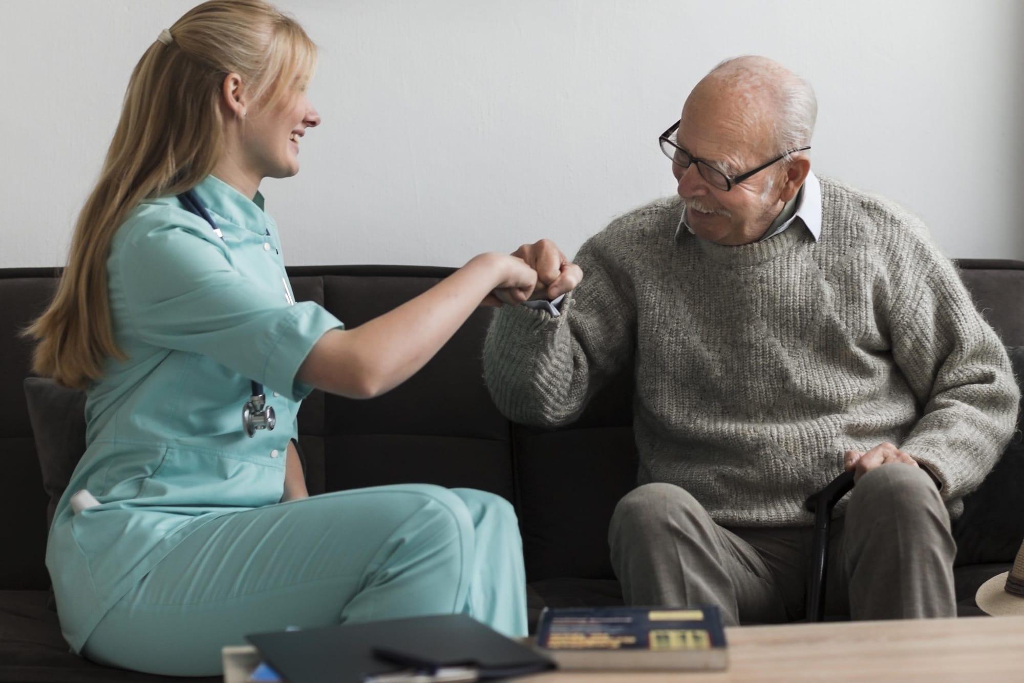 Older man in nursing home fist bumping a nurse